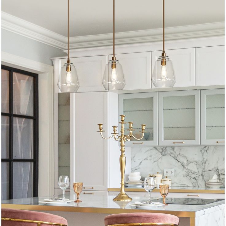 a kitchen with marble counter tops and gold bar stools next to a chandelier