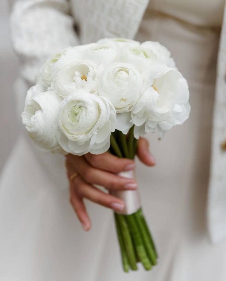 a woman holding a bouquet of white flowers