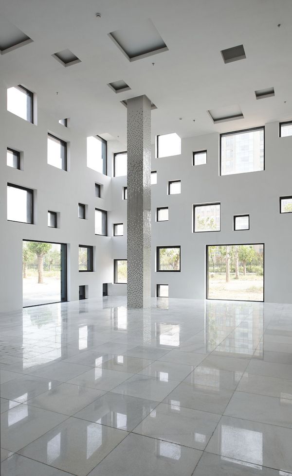 an empty room with large windows and white tile flooring in front of the wall