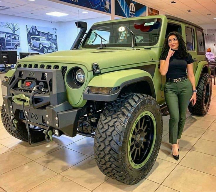 a woman standing next to a green jeep