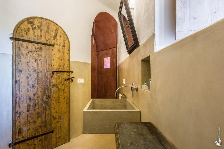 a bathroom with a wooden door and sink next to an open doorway that leads into another room