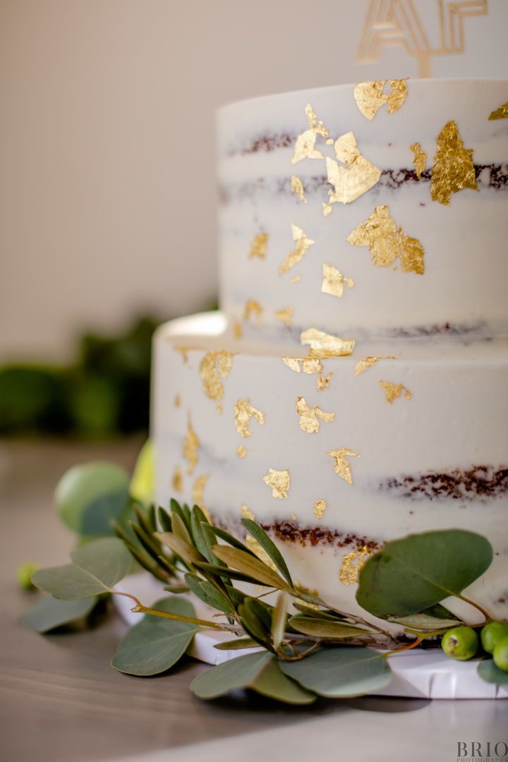 a white and gold wedding cake with greenery