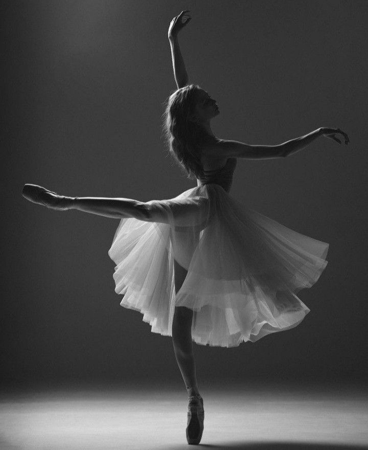 a woman in a white dress is dancing with her arms extended and legs spread out