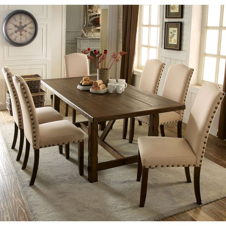 a dining room table and chairs with a clock in the background