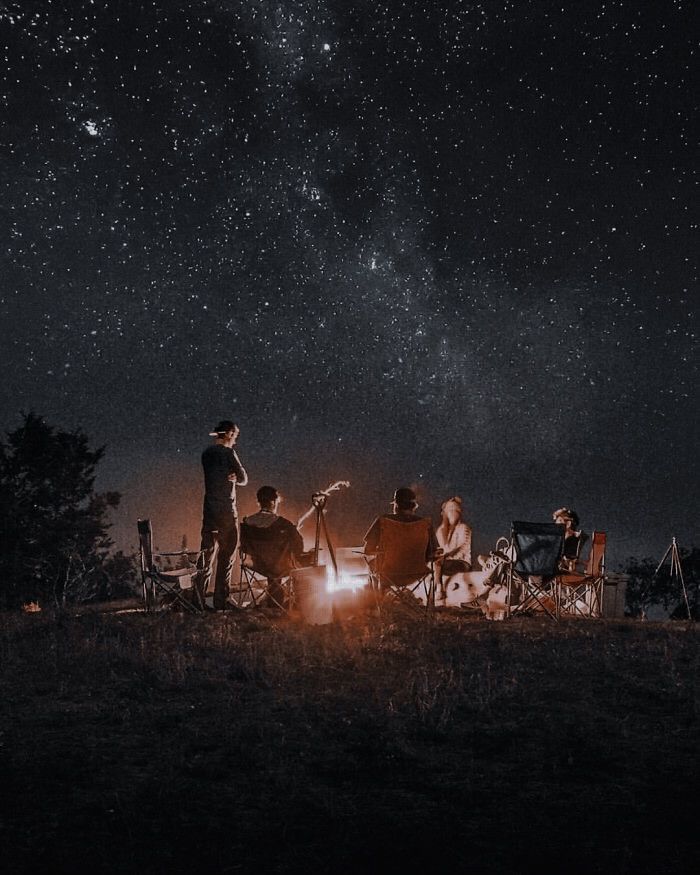 people sitting around a campfire under the stars