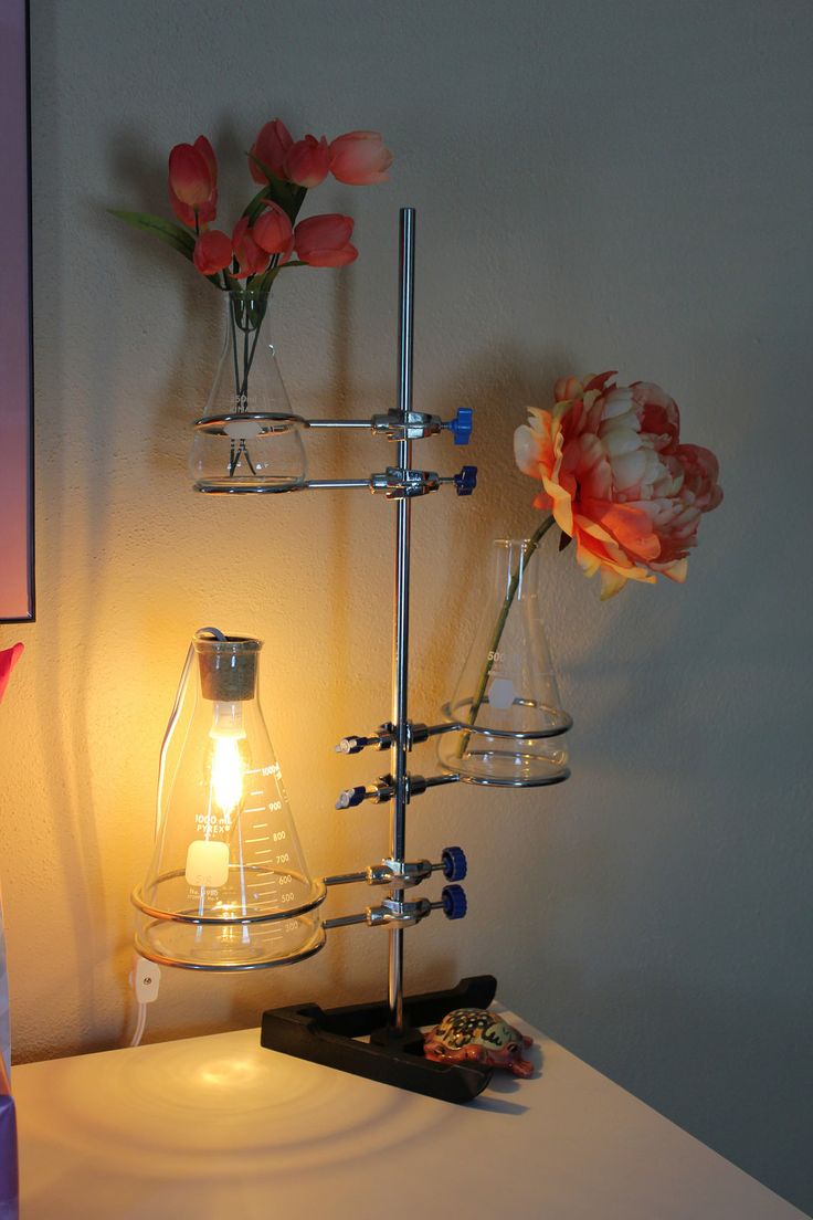 a lamp that is on top of a table next to a vase with flowers in it