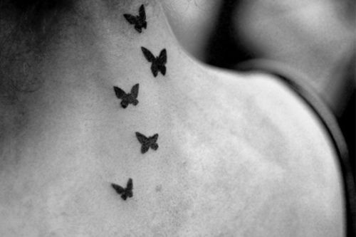 a woman's back neck with black butterflies on the upper part of her body