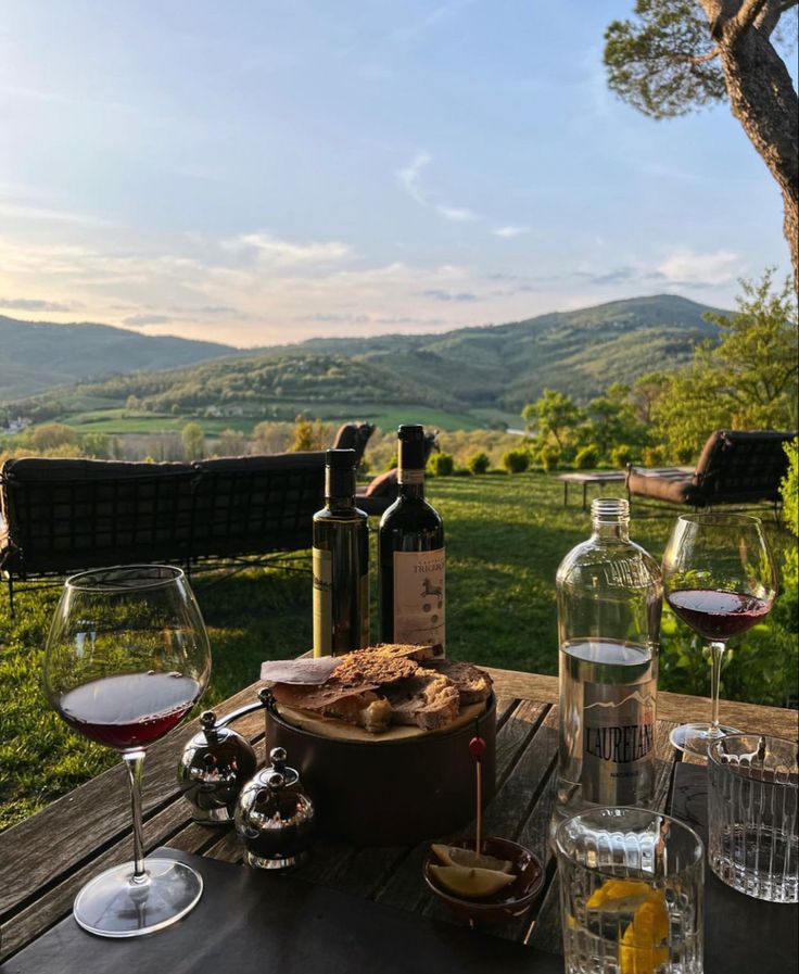 an outdoor table with wine and food on it