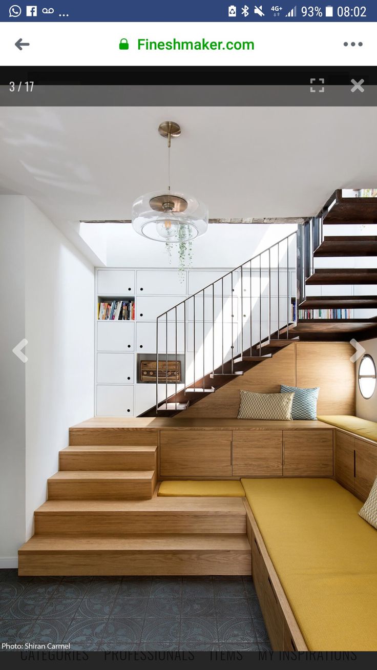 a room with some stairs next to a couch and bookshelf on the wall