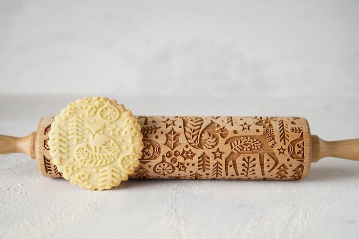 a wooden rolling pin with an intricate design on the side and a carved cookie in the middle