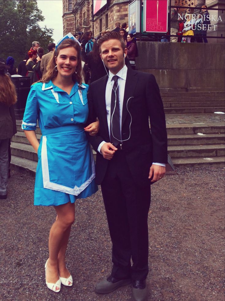 a man in a suit and tie standing next to a woman wearing a blue dress