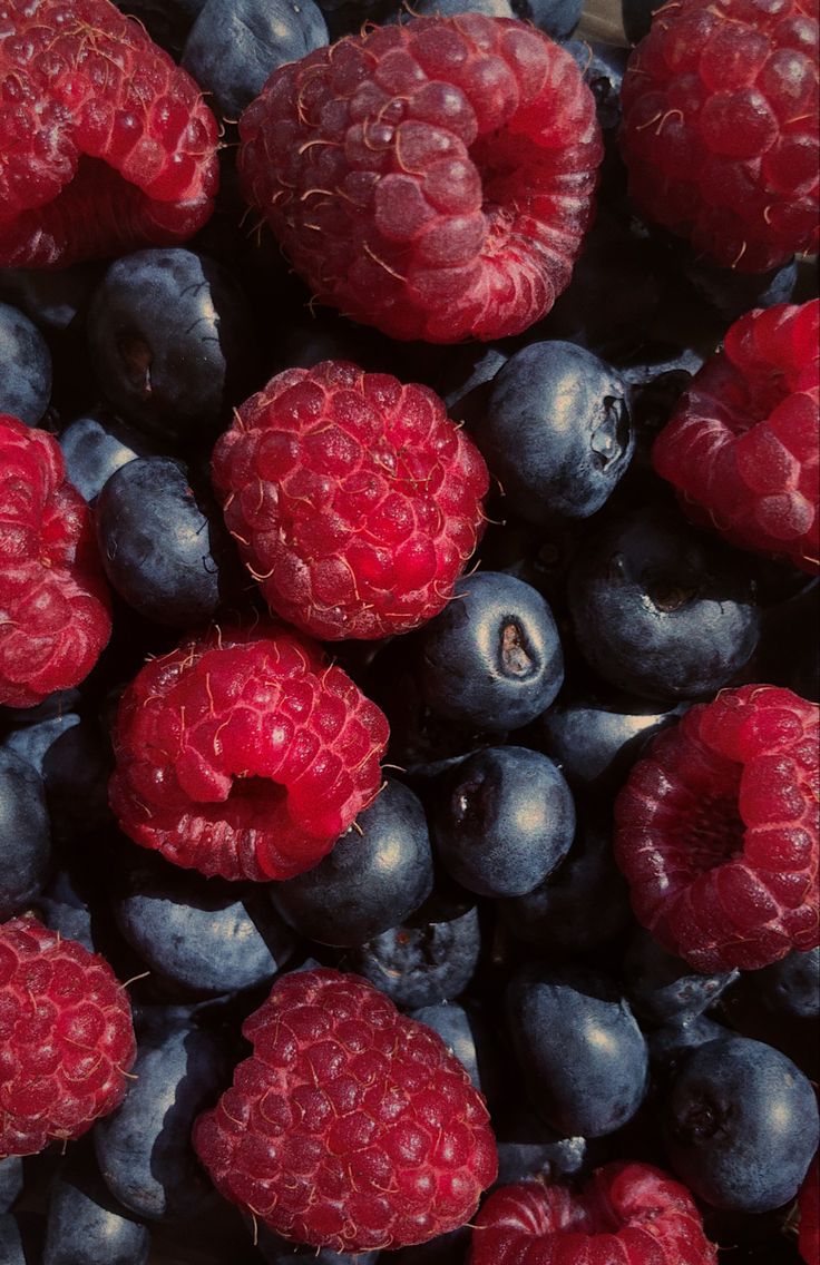 blueberries and raspberries are piled up together