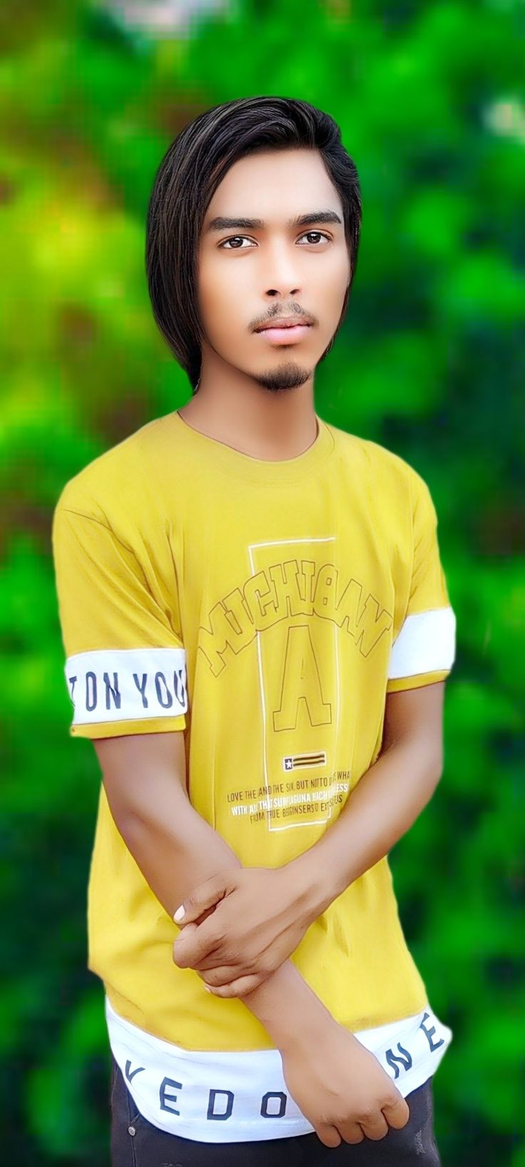 a young man in a yellow shirt is posing for a photo with his hand on his chest