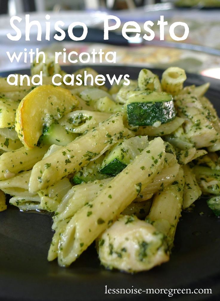 pasta with pesto and cashews on a black plate