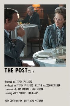 a man and woman sitting at a table in front of a poster for the post