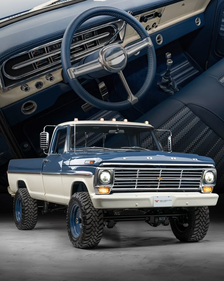 an old blue truck is parked in front of a car with the steering wheel up