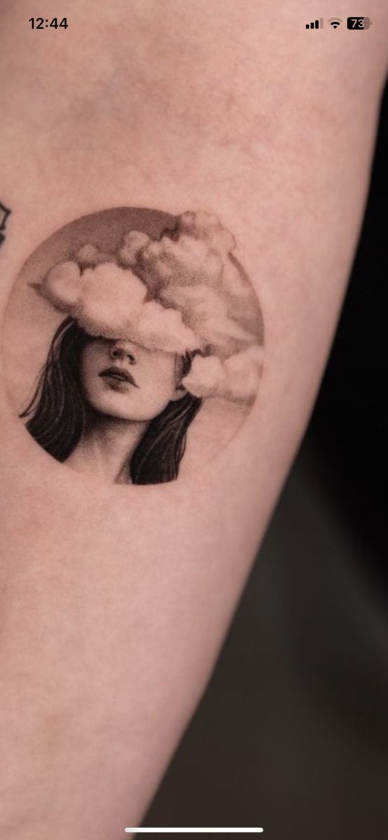 a woman's arm with a tattoo on it that has a cloud over her head