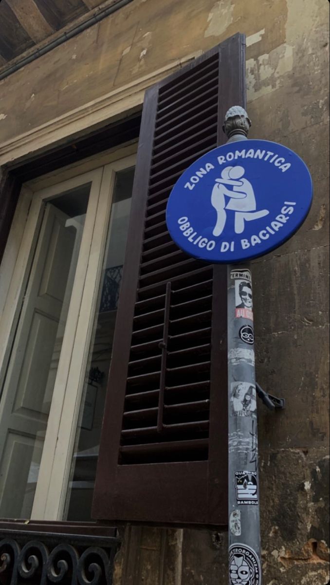 a blue street sign sitting on the side of a building next to an open window