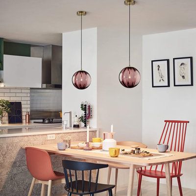 a dining room table and chairs in front of a kitchen counter with pictures on the wall