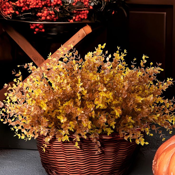 a basket filled with lots of yellow flowers next to pumpkins and other autumn decorations