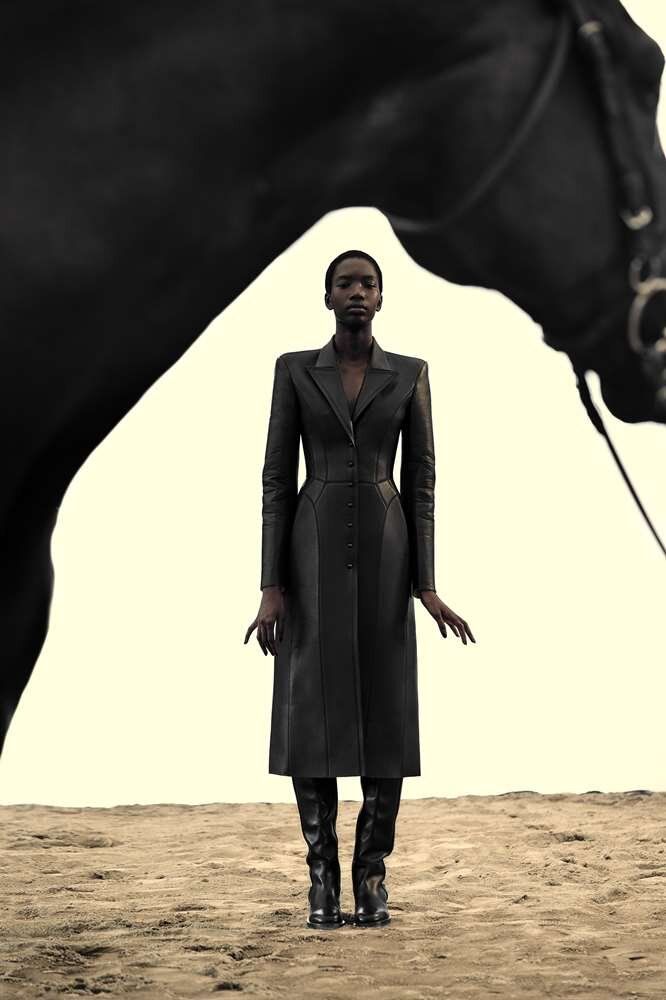 a woman standing in front of a black horse