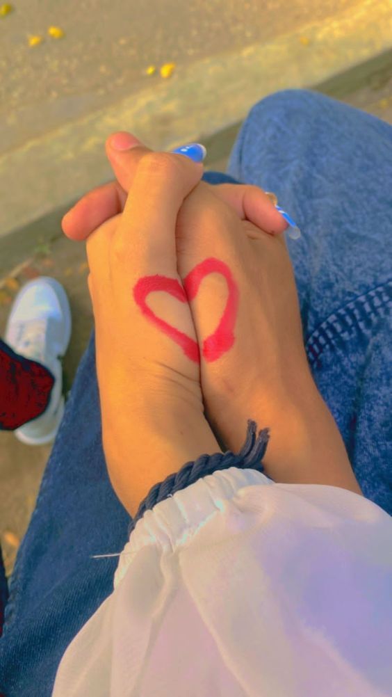 two people are holding hands with the word love painted on their wrist and one has a heart drawn on it