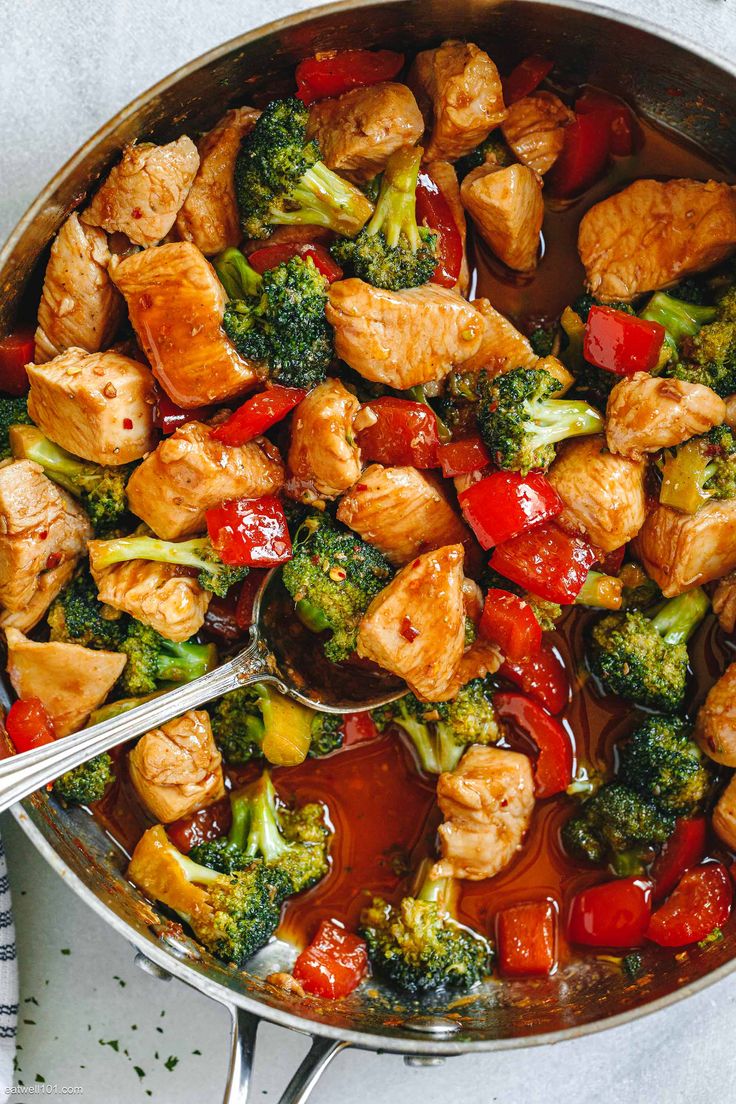 chicken and broccoli stir fry in a skillet with tongs on the side