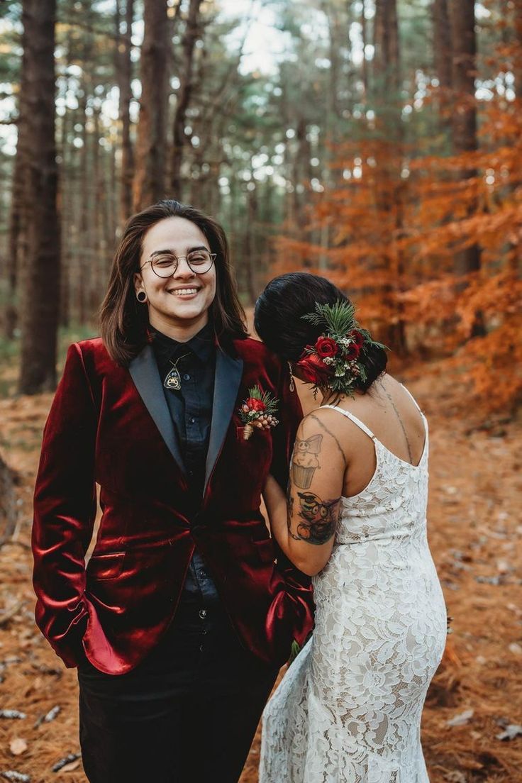 a woman in a red velvet jacket and black dress standing next to another woman