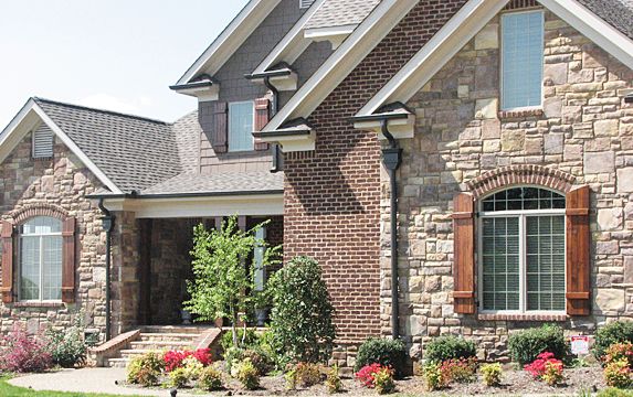 a brick house with flowers in the front yard