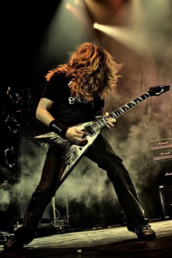 a man with long hair playing an electric guitar