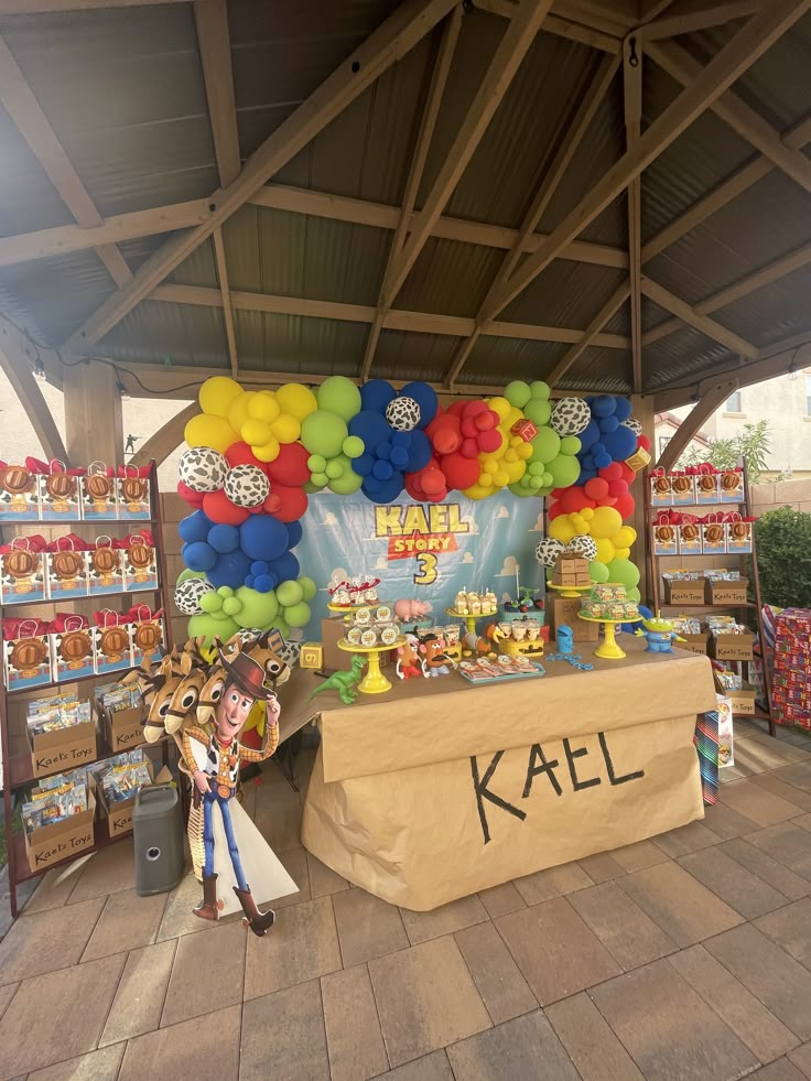 a table with balloons and cake on it in the middle of a market area for sale