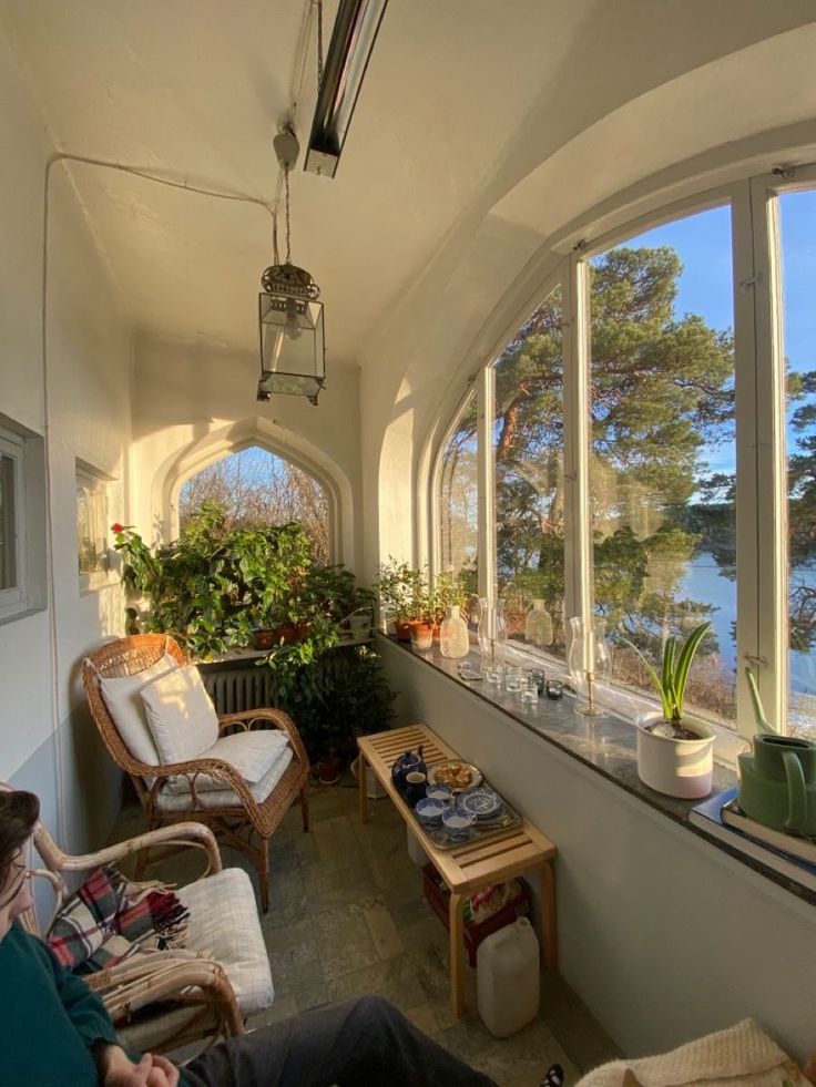 a man sitting on a couch in front of a window with lots of windows looking out onto the water