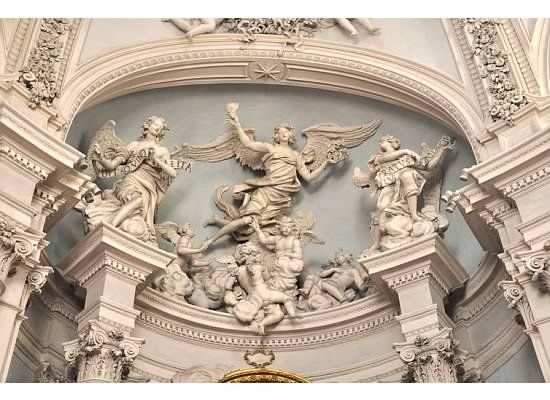 an ornate building with statues on the front and back walls, including angels above them