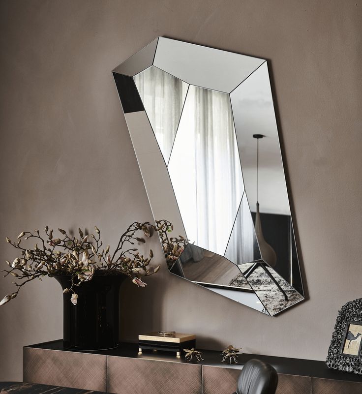 a mirror sitting on top of a dresser next to a vase filled with flowers