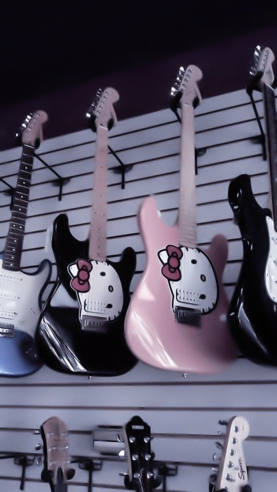 guitars with hello kitty heads are lined up on a rack in a music store or shop