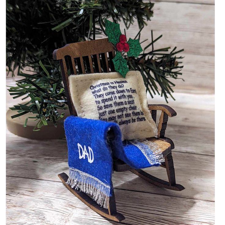 a wooden rocking chair with a blue blanket on it and a christmas tree in the background