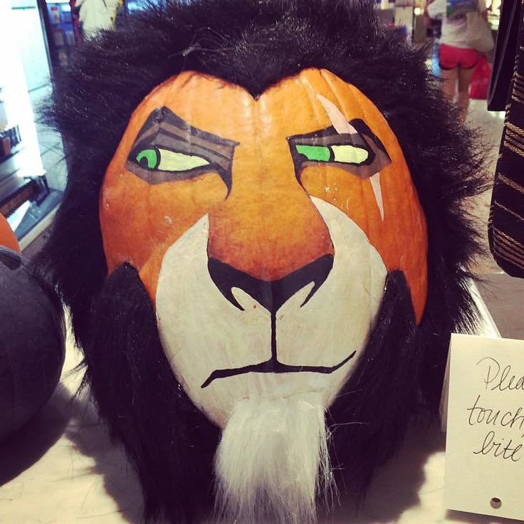 a lion mask with green eyes and white hair sits on a table next to a sign that reads, dear teacher's day