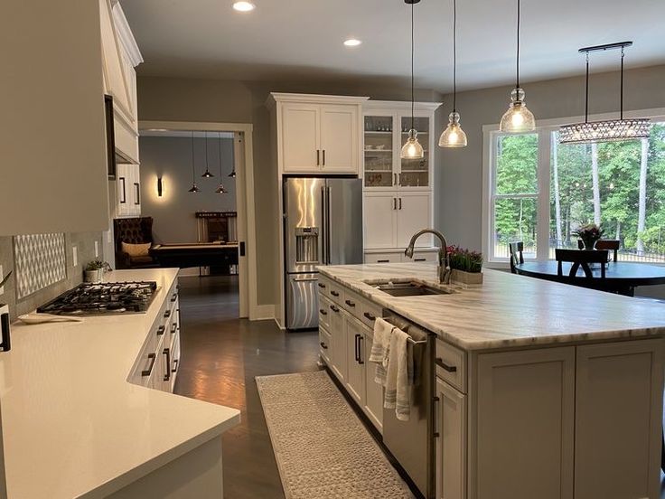 a kitchen with white cabinets and an island in the middle is lit by pendant lights