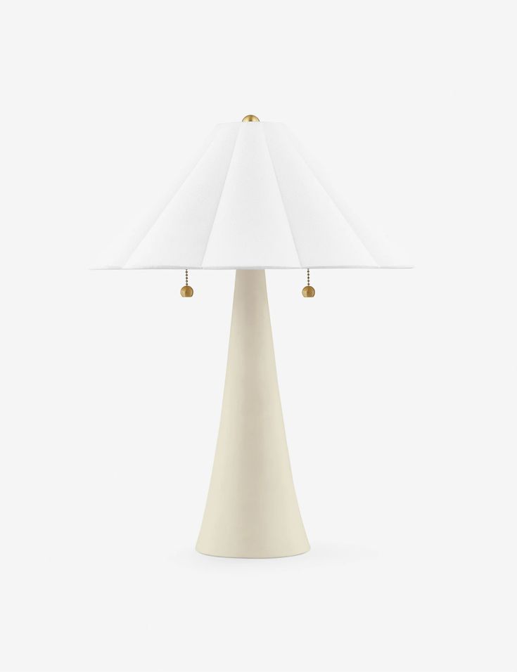 a table lamp with a white shade on the top and two gold bells at the base