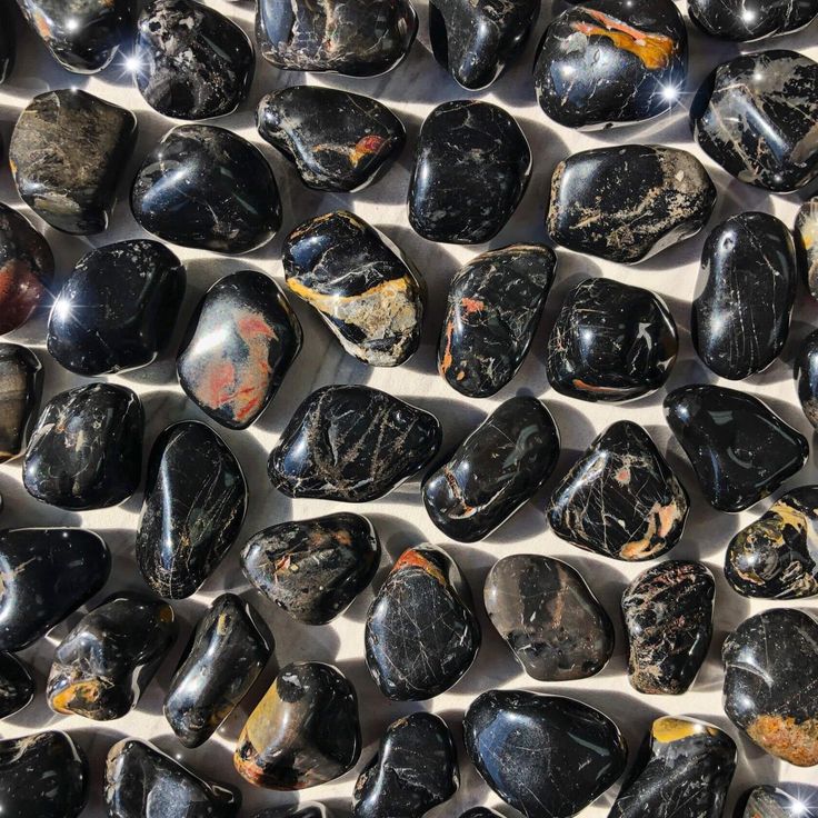 Small-sized, smooth, black, red, and yellow, Black Onyx tumbled pocket stones against a marbled background. Tumbled Crystals, Third Eye Opening, Colors Of Fire, Increase Intuition, Key Words, Raw Rose Quartz, Orange Crystals, Black Onyx Stone, White Crystals