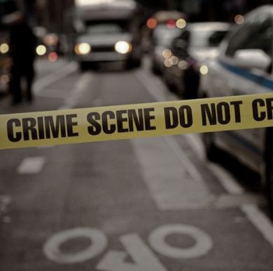 a police tape is taped off on the side of a street with parked cars behind it