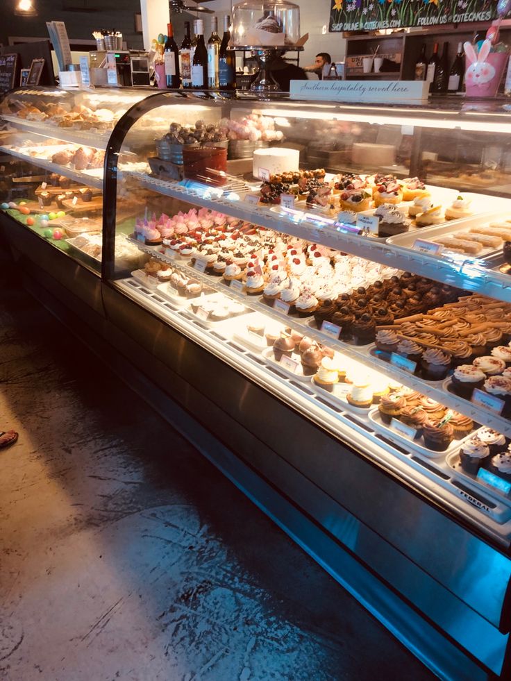 a display case filled with lots of different types of cupcakes and pastries