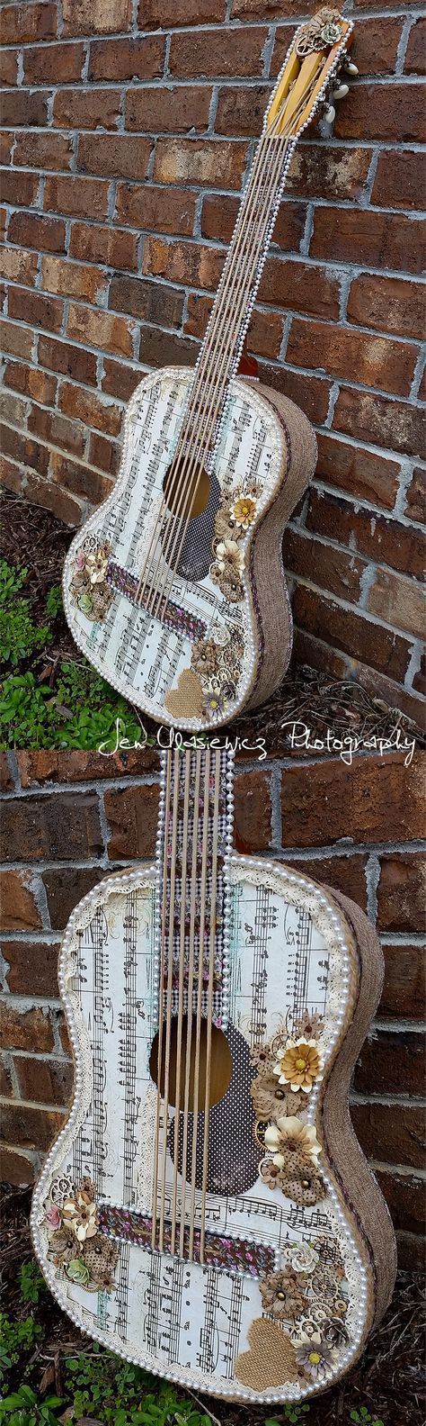 two guitars made out of sheet music are sitting on the ground next to a brick wall