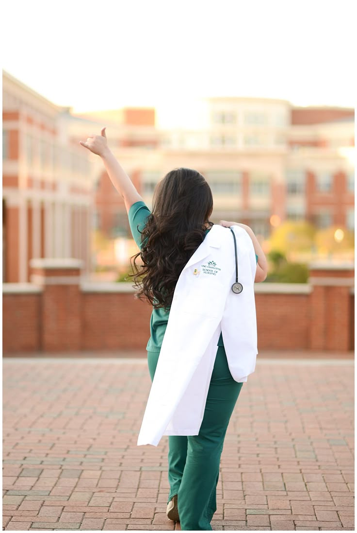 a woman in green pants and a white jacket is walking down the street with her arms outstretched