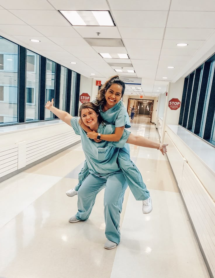 two women in scrubs are posing for the camera while holding their arms around each other