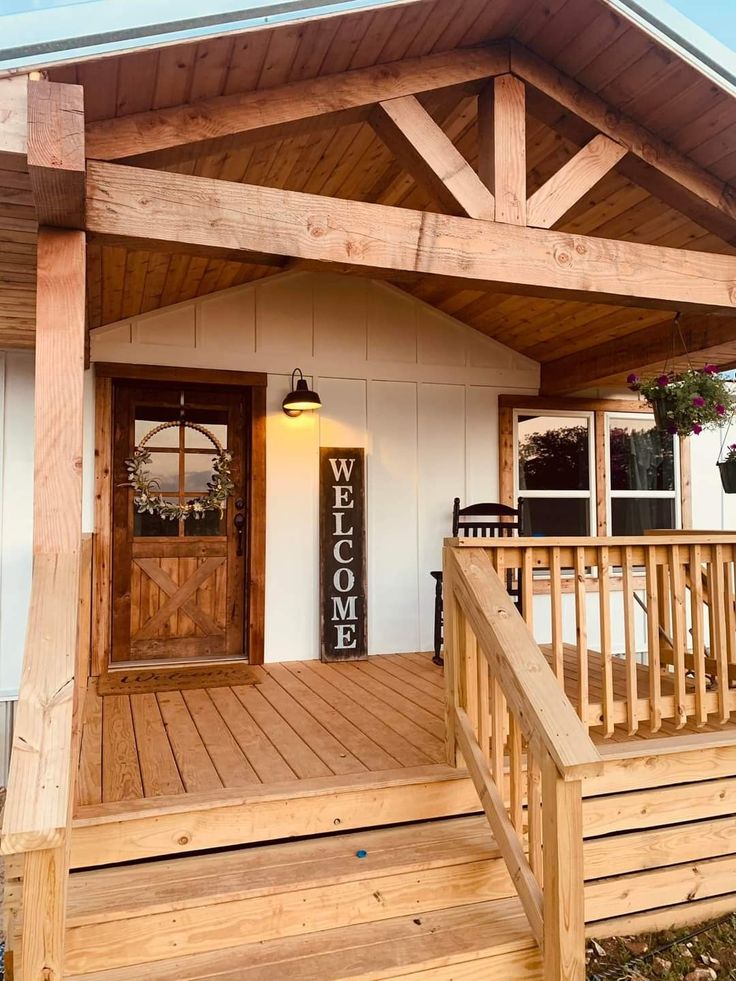 a wooden porch with steps leading up to the front door and entry way that has a welcome sign on it