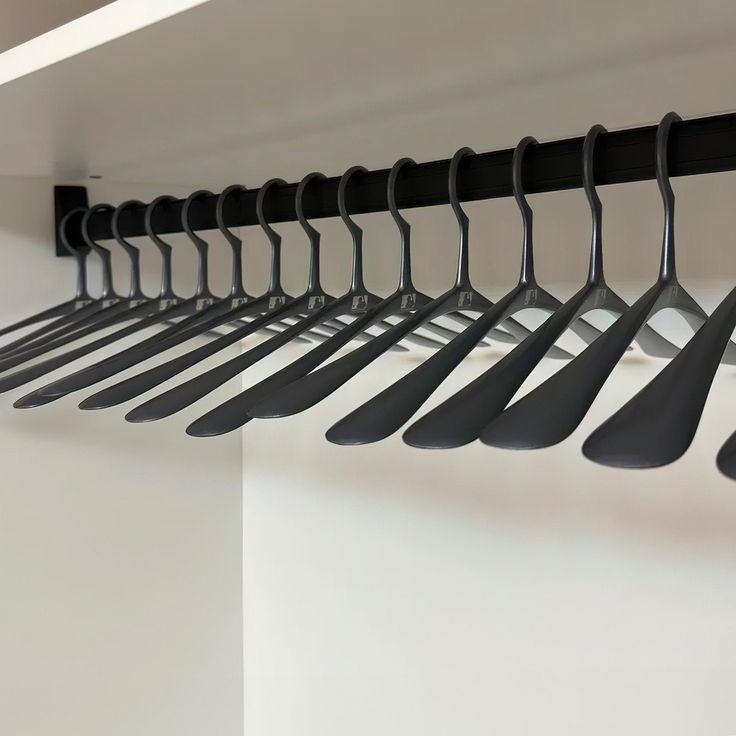 there are many black spoons hanging from the hooks on the wall in this room