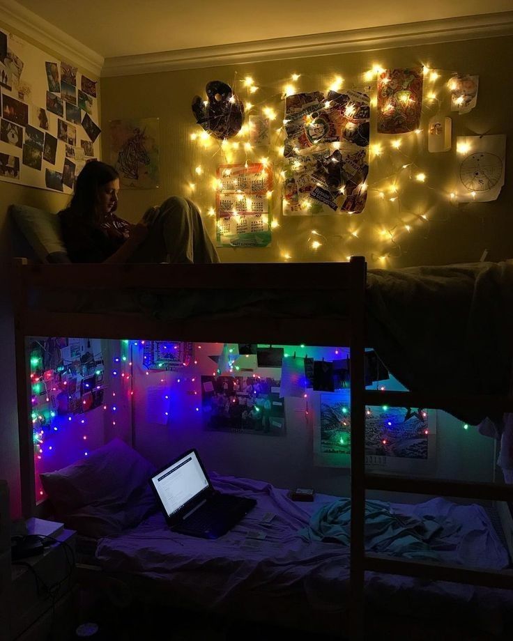 a woman sitting on top of a bunk bed in a room with lights all around her