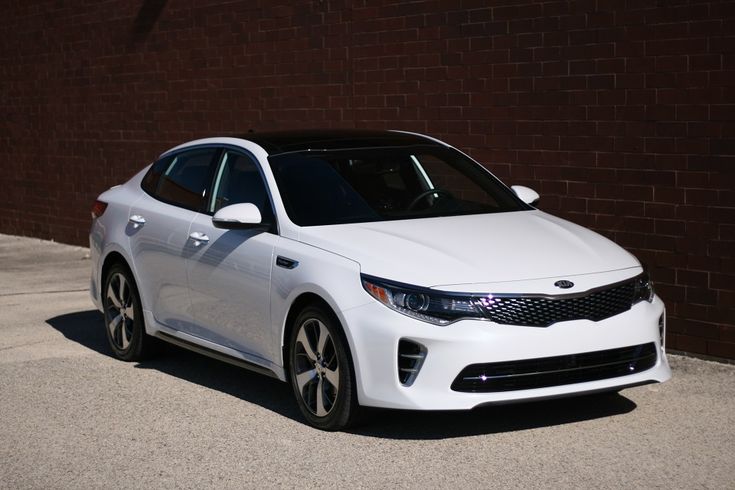 a white car parked in front of a brick wall