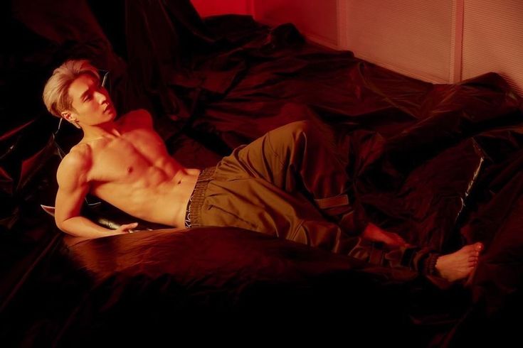 a shirtless man laying on top of a bed